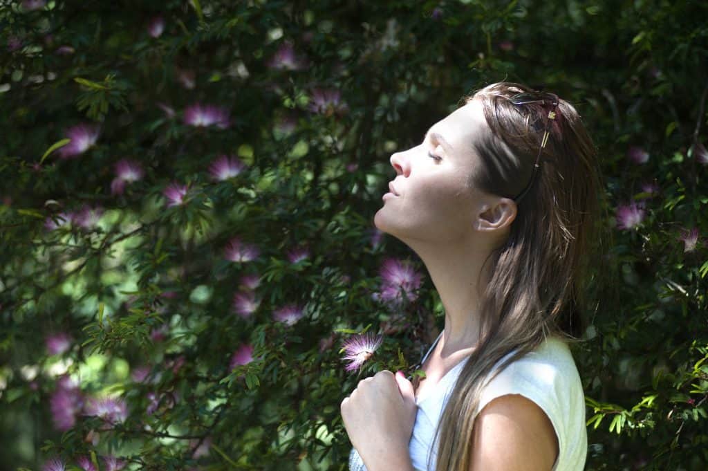 mom taking some alone time outdoors with eyes closed, looking relaxed